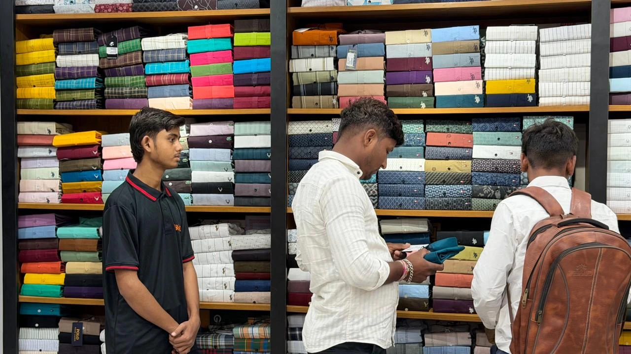 Store associate assisting customers as they examine a shirt beside stocked apparel shelves