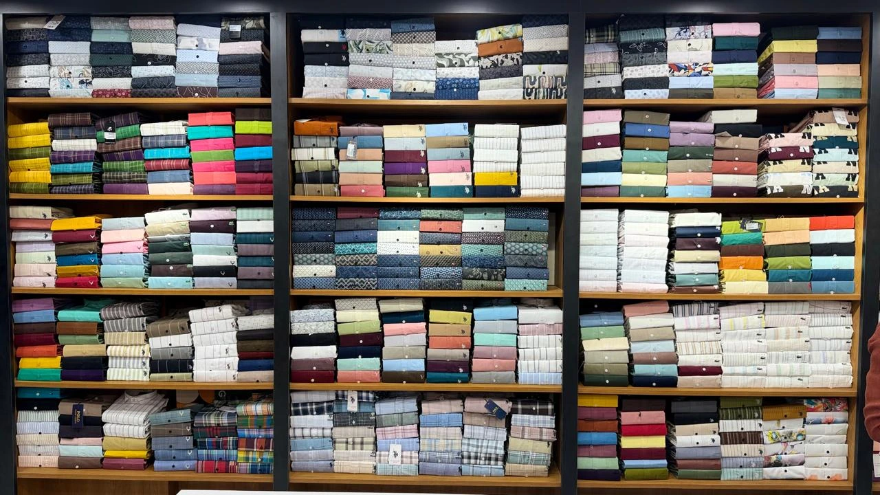 Rows of folded shirts in assorted colours on Maaax store shelves